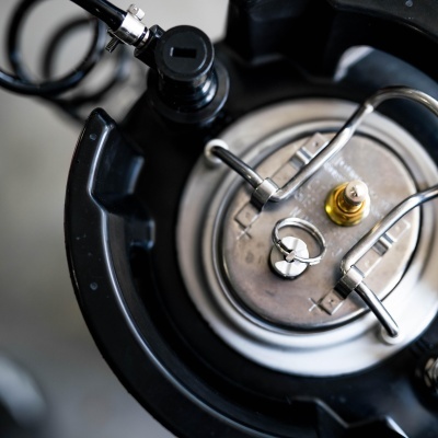 Tanque metálico com tampa de aço e válvula conectado a mangueira