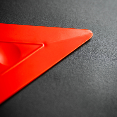 Régua triangular vermelha em plástico sobre superfície preta texturizada