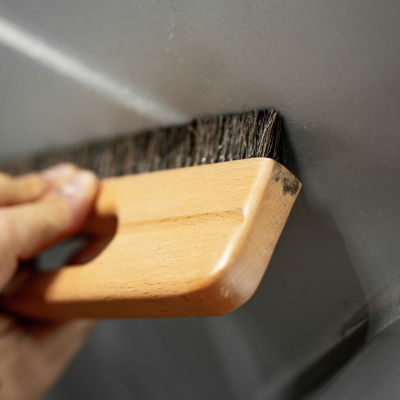 Pincel de cabo de madeira e cerdas escuras a limpar superfície cinza