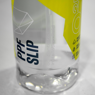 Frasco transparente com líquido e rótulo cinza e amarelo com texto