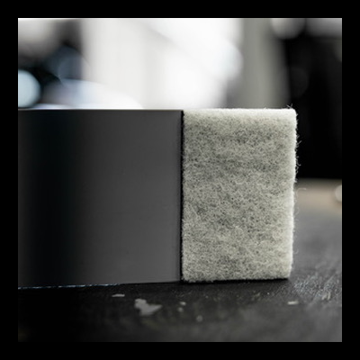 Esponja cinzenta macia ao lado de superfície preta sobre mesa escura