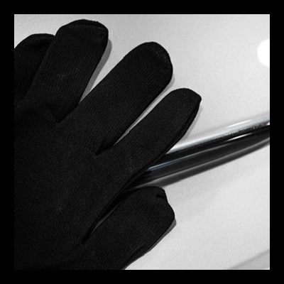 Luvas pretas de tecido sobre superfície branca brilhante com peça metálica