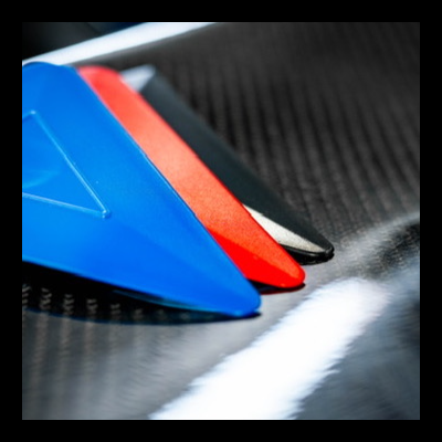 Três raspadores plásticos coloridos sobre superfície preta texturizada