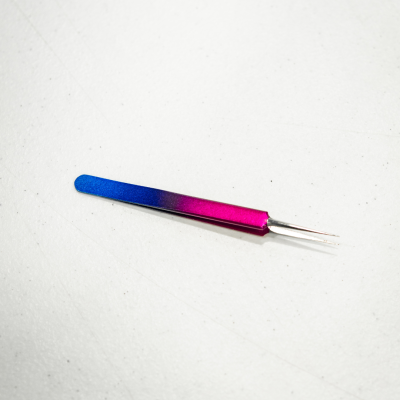 Pinça metálica com gradiente azul a rosa sobre fundo branco