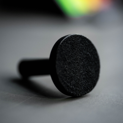 Cabo preto cilíndrico com base texturada sobre superfície cinzenta