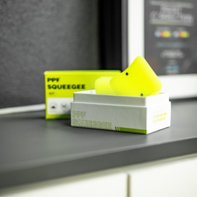Espátulas amarelas fluorescentes com caixas e texto PPF SQUEEGEE sobre superfície cinza interior