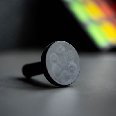 Suporte redondo preto com superfície plana e padrões circulares em fundo desfocado