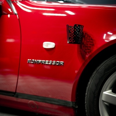 Detalhe lateral de carro vermelho com texto KOMPRESSOR