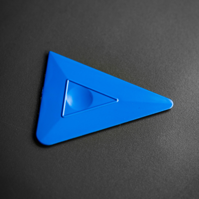 Triângulo adesivo azul com relevo no centro sobre superfície cinzenta