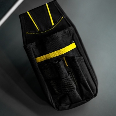 Bolsa preta para ferramentas com detalhes amarelos sobre superfície cinzenta