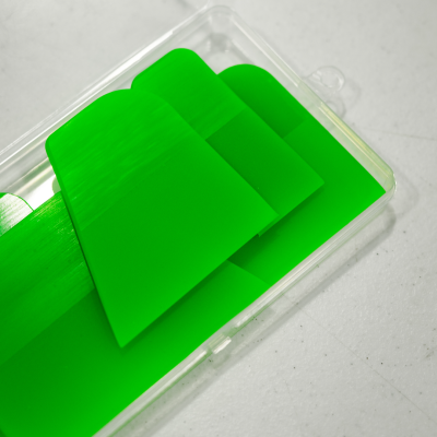 Três espátulas verdes de plástico numa embalagem plástica transparente