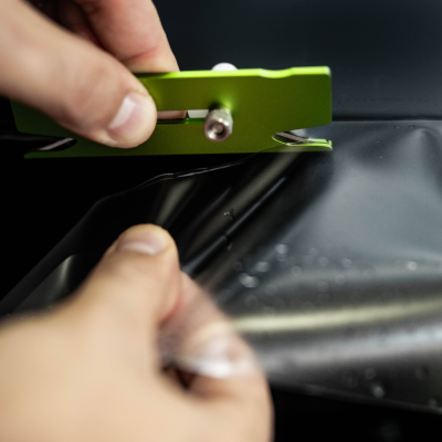 Mão segura ferramenta verde perto de superfície preta com película transparente