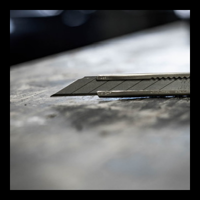 Faca de precisão com lâmina preta numa superfície rústica