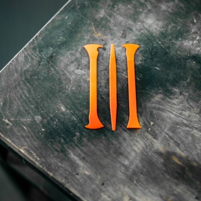 Três ferramentas de plástico laranja sobre superfície escura