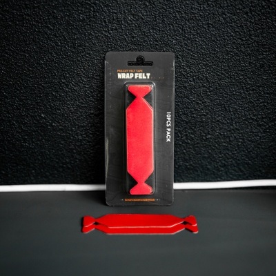Pacote de tiras vermelhas de feltro WRAP FELT em cartaz preto, uma tira vermelha fora da embalagem sobre superfície preta