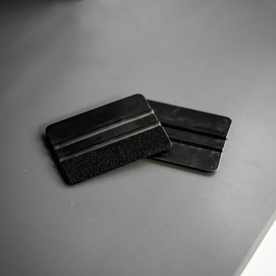 Dois aplicadores pretos para vinil sobre superfície cinzenta