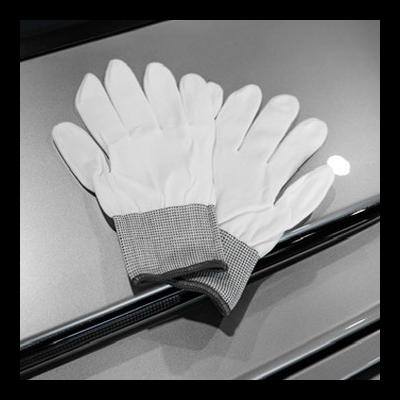 Par de luvas brancas com punho cinza sobre superfície metálica cinza