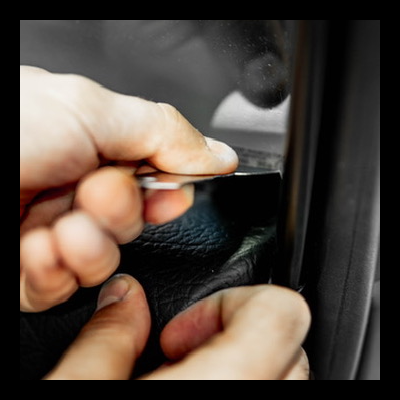 Ferramenta metálica entre mãos e superfície de couro preto dentro de veículo