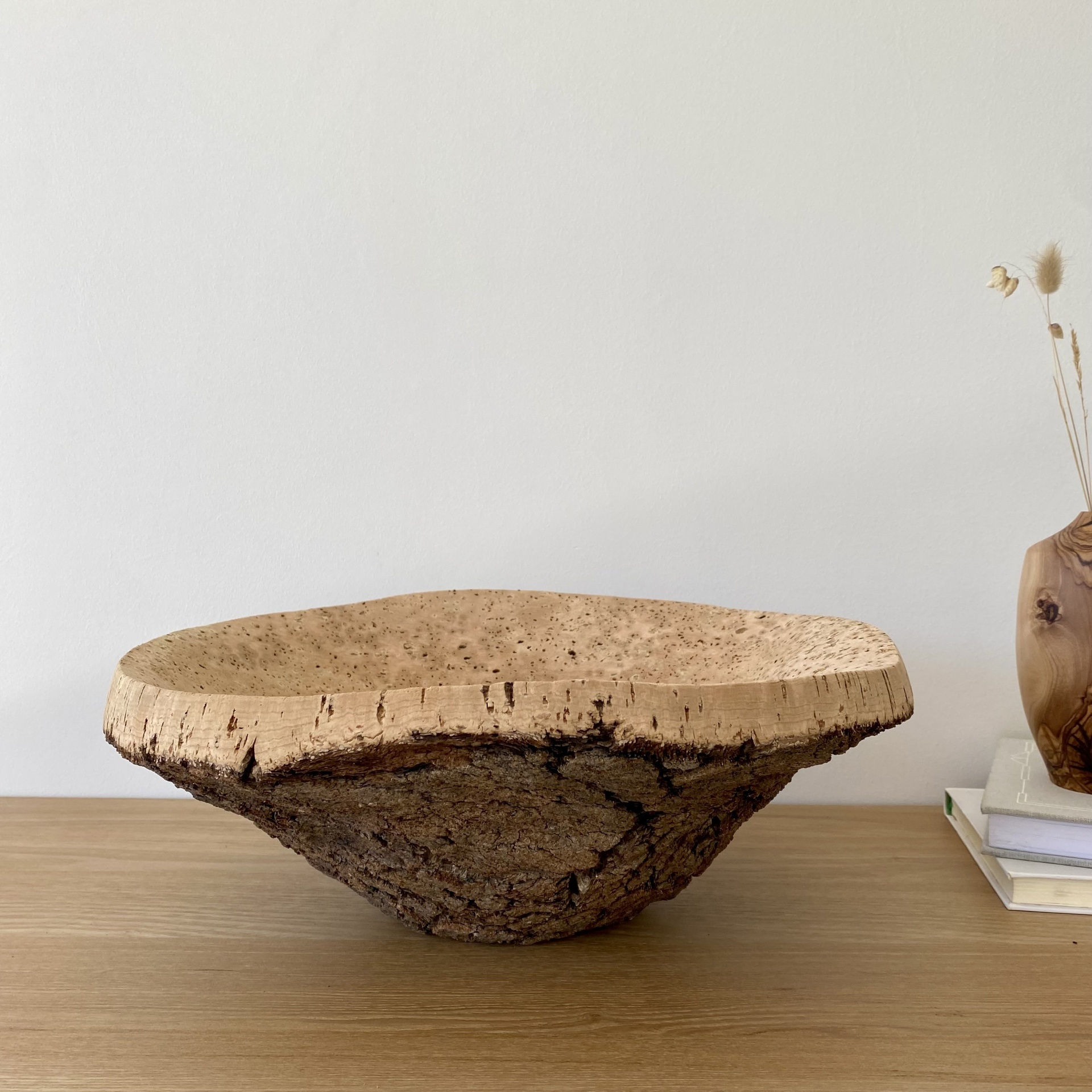 TAÇA EM CORTIÇA NATURAL Tigela rústica de madeira natural sobre mesa com vaso e livros ao lado
