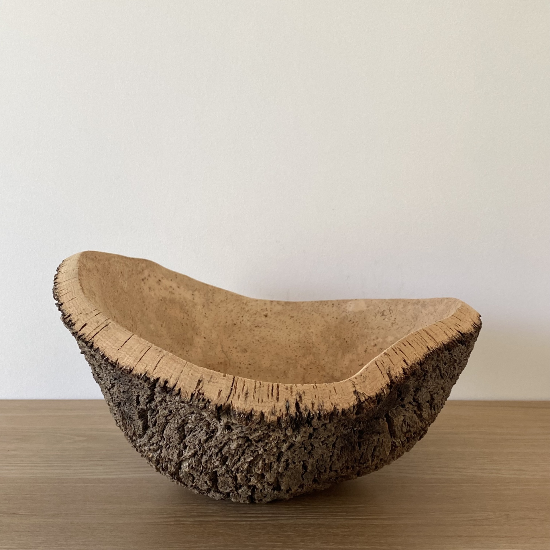 TAÇA EM CORTIÇA NATURAL Cestinho de cortiça com textura rugosa exterior e interior liso sobre mesa de madeira clara