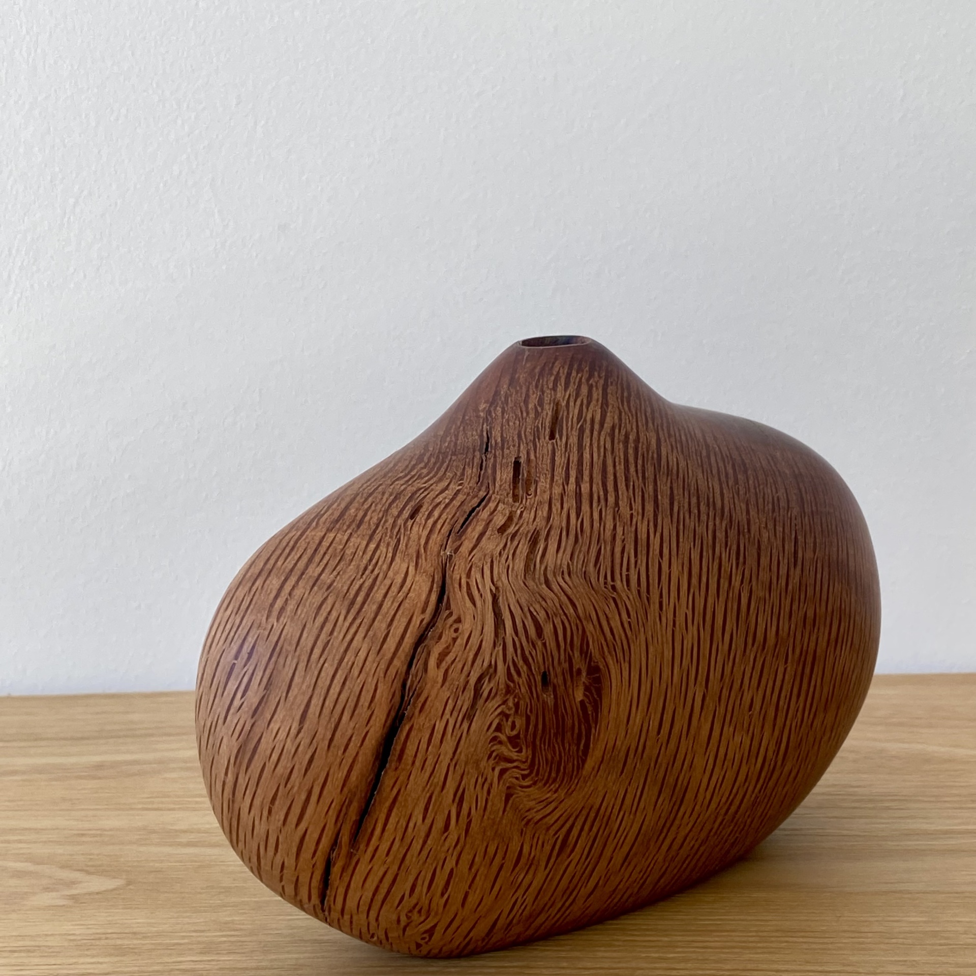 JARRA EM MADEIRA DE AZINHO Jarro em madeira castanha com textura natural e formato arredondado sobre superfície de madeira clara
