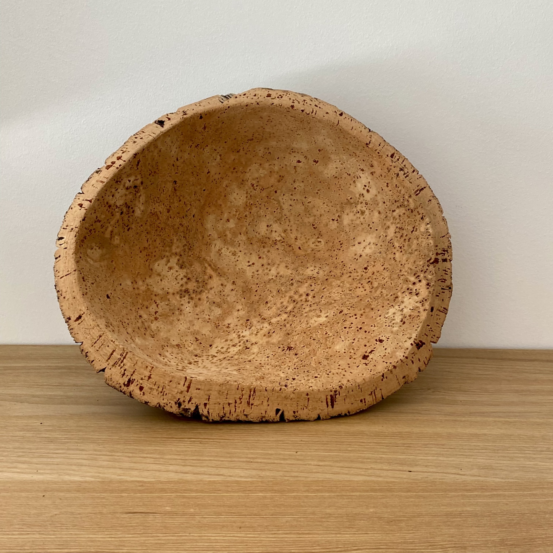 TAÇA EM CORTIÇA NATURAL Tigela de cortiça natural com textura irregular sobre superfície de madeira