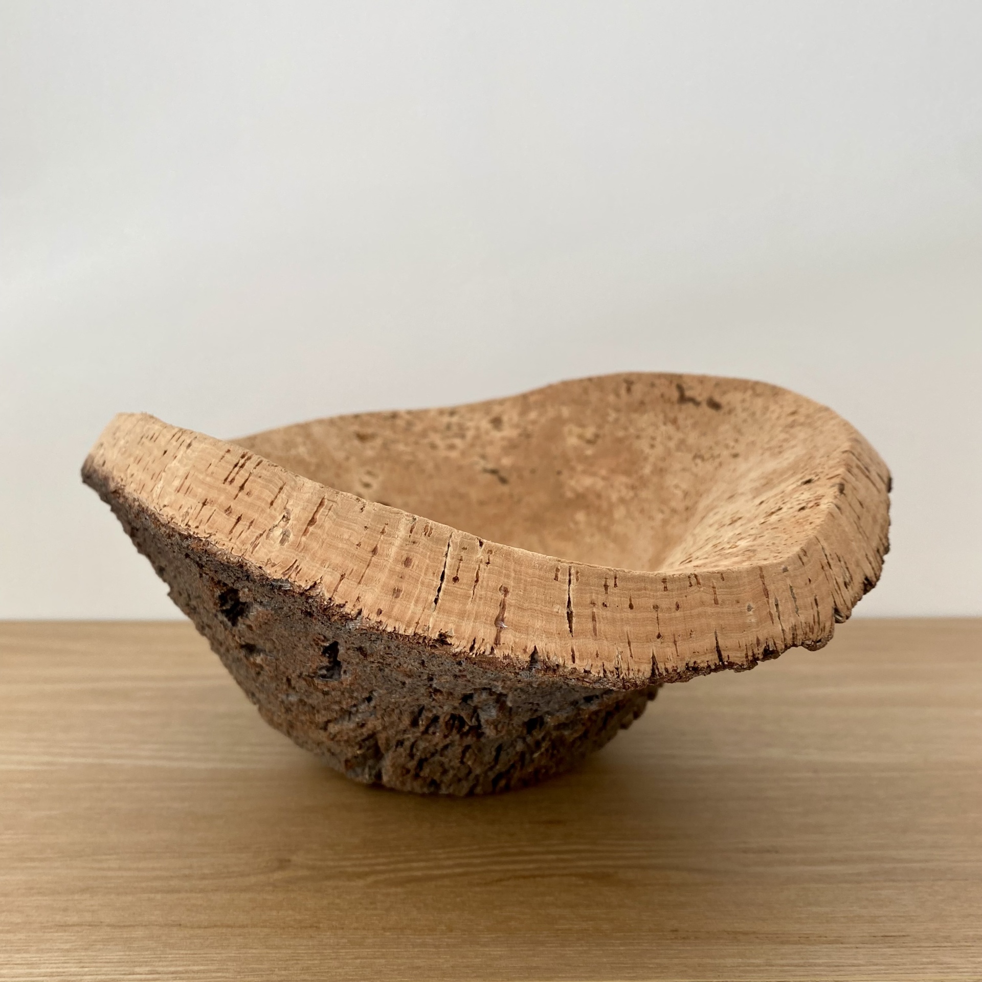 TAÇA EM CORTIÇA NATURAL Tigela irregular de cortiça sobre superfície de madeira clara