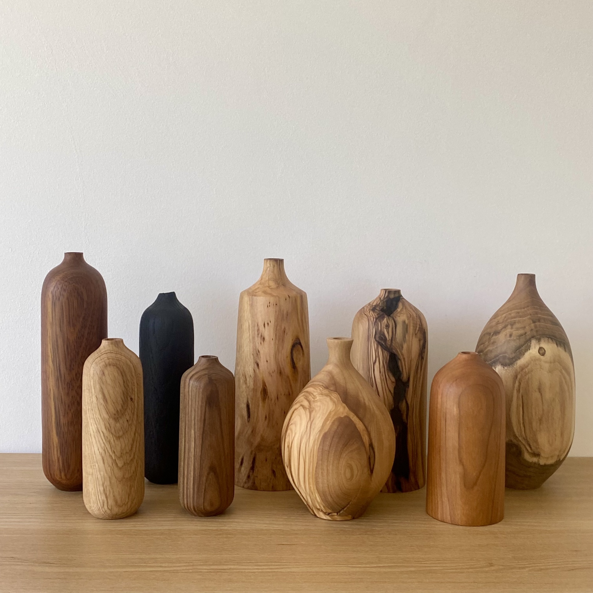 JARRA EM MADEIRA DE CEREJEIRA Conjunto de 9 vasos decorativos em madeira de vários tons arranjados sobre mesa