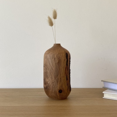 Vaso alto de madeira com ramos secos numa mesa com livros ao lado