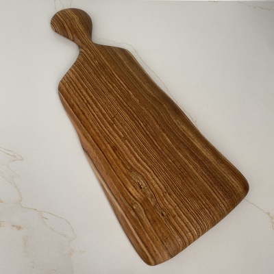 Tábua de cortar em madeira castanha com pega arredondada sobre superfície branca