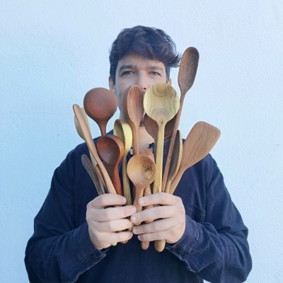 Pessoa com várias colheres e espátulas de madeira nas mãos