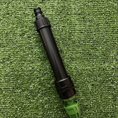 Aspersor de irrigação preto e verde sobre relva artificial
