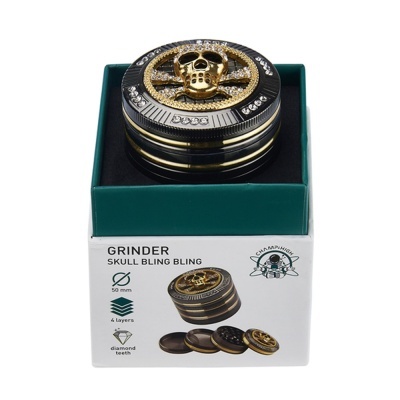 Moinho preto e dourado com crânio brilhante numa caixa verde e branca