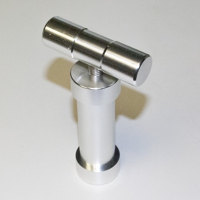 Peça metálica prateada cilíndrica com parte superior em T sobre fundo branco