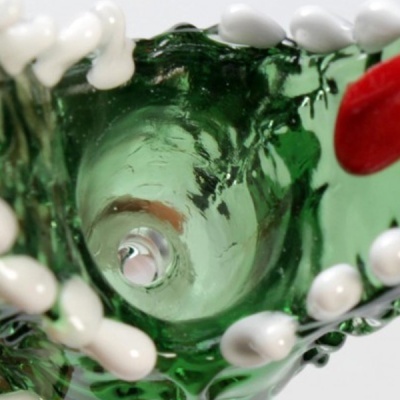 Interior de vaso em vidro verde com detalhes em branco e vermelho