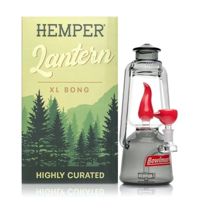 Bong de vidro transparente com base cinza e detalhes vermelhos ao lado da embalagem com desenho de floresta e texto Hemper Lantern XL Bong