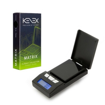 Balança digital compacta preta KEEX Matrix com tampa aberta ao lado da embalagem preta e verde.