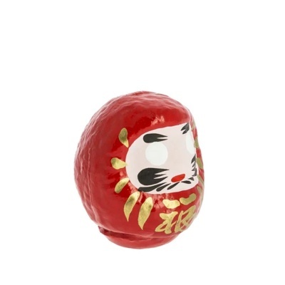 Boneco Daruma vermelho em papel machê com rosto pintado.