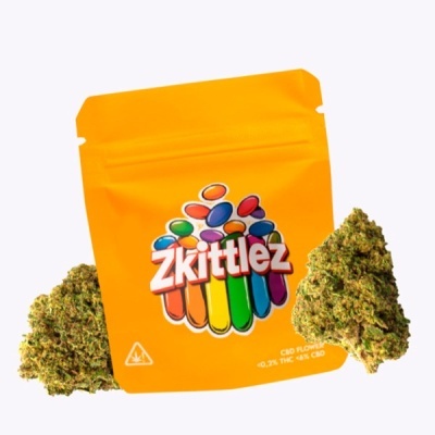 Embalagem amarela Zkittlez com flores de CBD e duas flores secas verdes