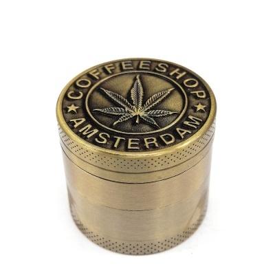 Moedor metálico dourado com gravação de folha de cannabis e texto COFFEESHOP AMSTERDAM