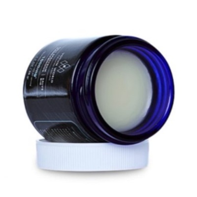 Recipiente de vidro azul com creme branco e tampa branca
