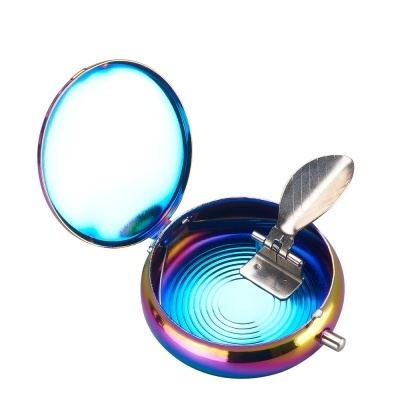 Caixa metálica iridescente redonda com interior azul e presilha de metal em forma de folha