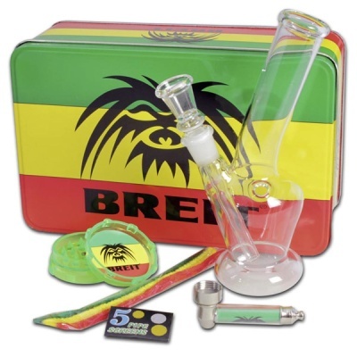 Conjunto de acessórios para fumar com bong de vidro, caixa metálica tricolor com texto BREIT, triturador e ferramentas coloridas.