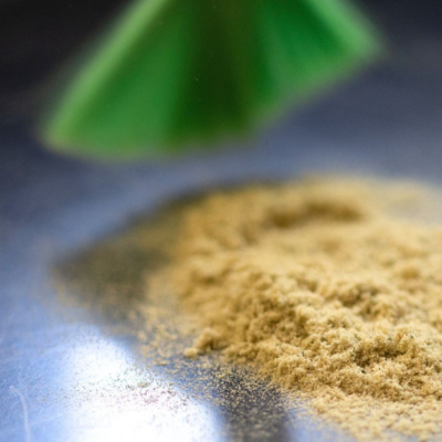 Pó amarelo claro sobre superfície metálica com objeto verde desfocado ao fundo