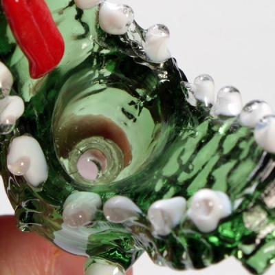 Peça de vidro verde com relevo branco e detalhes vermelhos