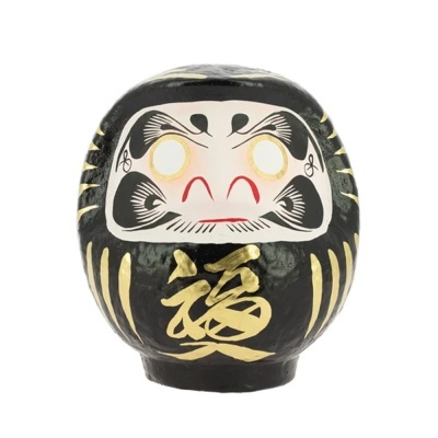 Figura Daruma preta com detalhes dourados e expressão facial pintada