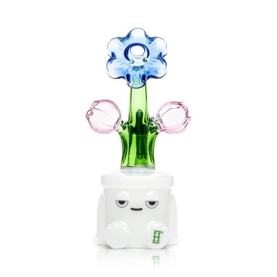 Objeto decorativo em vidro com flores azuis, rosas e verdes saindo de uma base branca com cara sorridente