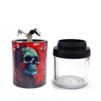 Moedor de ervas com caveira azul em fundo vermelho e compartimento transparente com tampa preta
