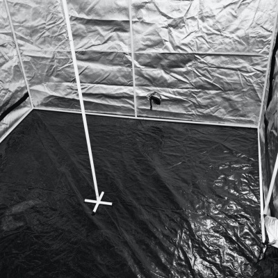 Interior de barraca de cultivo com paredes refletoras prateadas e piso preto