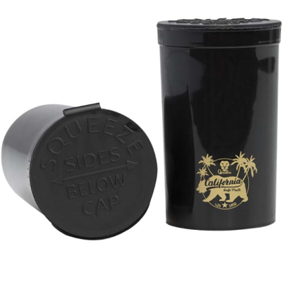 Dois recipientes pretos cilíndricos com tampa, um com etiqueta dourada com texto e desenhos de palmeiras.